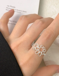 Macro shot of silver hollow floral ring featuring delicate interlaced petals on finger