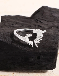 Macro shot of silver S925 heart ring with sunburst radial texture on a black charcoal base