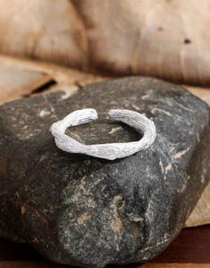 Détail de la bague croisée en argent S925 avec texture martelée sur pierre sombre