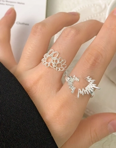 Detail of S925 sterling silver rings with abstract hollow flower and star designs on fingers