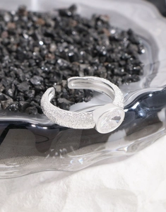 Detailed view of S925 silver ring with oval zircon on a wavy glass tray