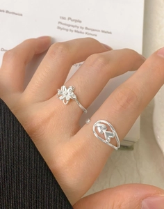 Détail de bagues ajustables en argent S925 avec motifs fleur et cœur sur les doigts