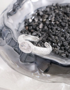 Macro shot of silver hammer texture ring with oval zircon on black mineral stone background