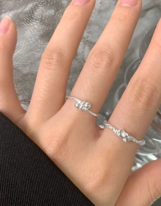 Primo piano di anelli a sfera in argento sterling S925 indossati con motivi a nodo