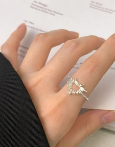 Macro shot of S925 sterling silver heart ring with sunburst design worn on model's finger