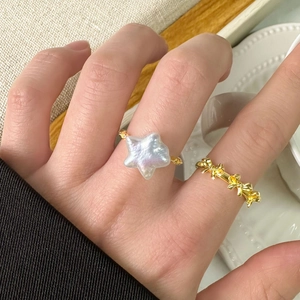 Bague en perle étoile dorée et bagues nœud empilables portées par un mannequin chic