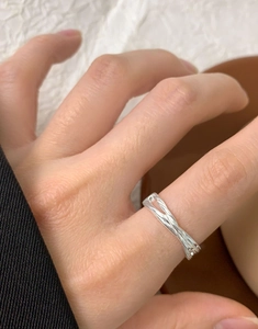 Detailed view of an irregular cross-wrap S925 silver ring on a finger with minimalist style