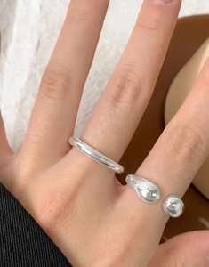 Dettaglio del set di anelli a goccia in argento S925 indossati sulle dita della modella