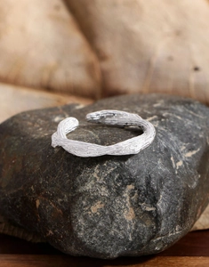 Vue macro d'une bague en argent S925 avec texture branche rustique sur pierre