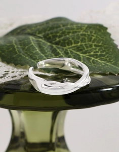 Detailed close-up of S925 sterling silver irregular twisted ring on a decorative glass base