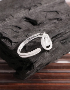 Macro detail of S925 sterling silver open heart ring on textured charcoal background