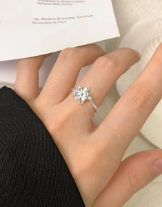 Gros plan d'une bague fleur double couche en argent S925 portée au doigt sur fond sombre