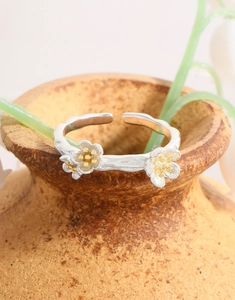 Detail of S925 silver flower ring with gold stamens resting on a ceramic vase