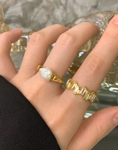 Close-up of golden baroque pearl ring and baguette-cut zircon band worn on hand