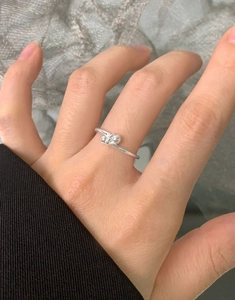 Dettaglio anello in argento minimalista con design a doppio nodo di sfere al dito