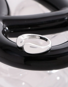Macro dell'anello regolabile a goccia in argento sterling S925 su superficie nera lucida