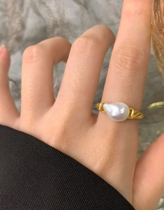 Detail of irregular baroque pearl ring with golden twisted rope band on finger