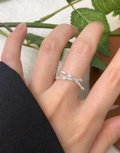 Detailed close-up of a silver crisscross bamboo textured ring on a hand