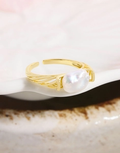 Detailed close-up of Baroque pearl ring with golden woven hollow band on white porcelain