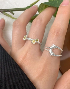 Detail view of S925 sterling silver flower and twisted knot rings on a model's hand