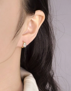 Gros plan d'une boucle d'oreille cœur dorée minimaliste sertie d'un zircon