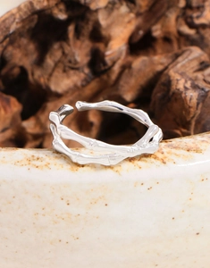 Macro shot of S925 sterling silver bamboo knot ring on a ceramic edge with wood decor