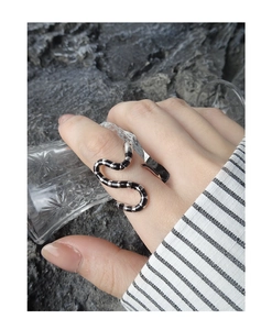 Detail of snake-shaped S925 silver ring with black enamel stripes on a stone background