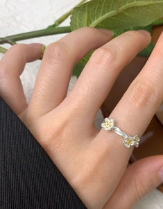 Detail of silver S925 flower ring with yellow stamens and plant texture band on hand