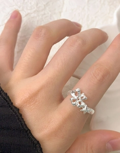 Detail shot of a S925 sterling silver ring with clover and star charms on finger
