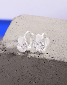Gros plan de boucles d'oreilles cœur en argent S925 avec zircon sur pierre grise