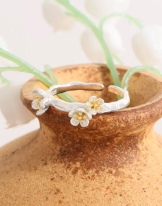 Macro shot of S925 sterling silver flower ring featuring gold petals and branch texture