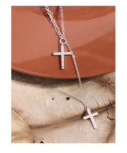Detailed close-up of double cross necklace with pavé zircon and polished finish