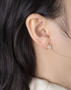 Gros plan d'une boucle d'oreille créole en or avec cœur en zircon brillant portée