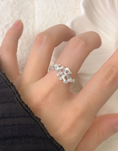 Close-up of elegant S925 sterling silver ring with irregular hollow floral design worn on finger