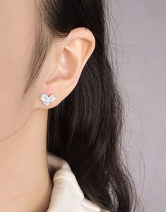Close-up of S925 silver camellia heart stud earring worn on model's earlobe