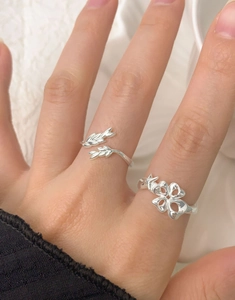 Detailed shot of two S925 sterling silver rings with leaf and clover designs on hand