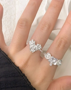 Detailed view of silver rose rings with a large heart-shaped crystal on female fingers
