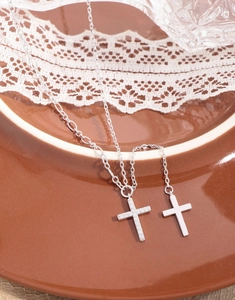 Close-up of S925 silver cross pendant necklaces with zircon inlay on a ceramic tray