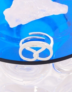 Macro shot of interlocking silver s925 heart knot ring on blue crystal decorative stone