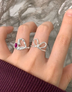 Gros plan sur bague en argent S925 avec zircon rouge et bague noeud au doigt
