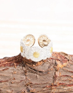 Macro shot of silver daisy open ring with yellow centers on rustic wood background