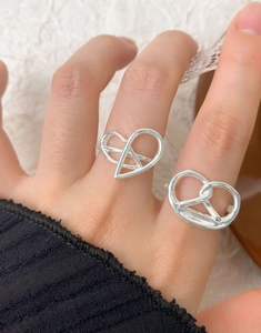 Close-up of S925 sterling silver heart and pretzel knot rings worn on finger