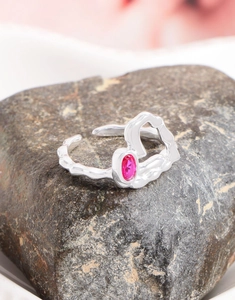 Macro d'une bague en argent S925 avec zircon rose et texture de lave irrégulière sur roche