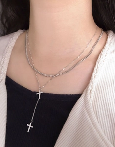 Macro detail of silver layered cross pendants on a curb and cable chain necklace