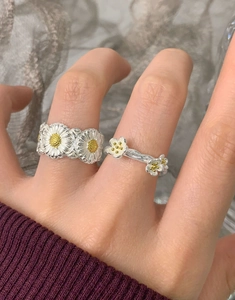 Detail of two S925 sterling silver daisy flower rings worn on a hand in a macro view