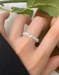 Detail of twisted S925 silver ring with zircons and brushed matte finish on hand