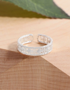 Macro shot of silver adjustable open ring with hollowed-out star pattern on wood