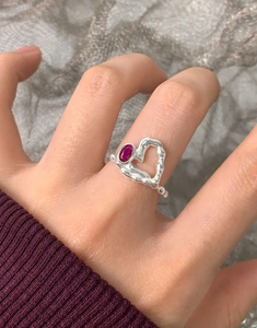 Détail macro d'une bague en argent S925 avec cœur irrégulier et zircon rouge