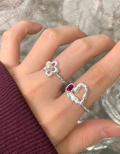 Gros plan de bagues en argent S925 avec fleur de perle et cœur rubis sur le doigt