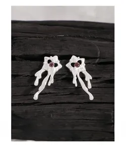 Détail de boucles d'oreilles en argent S925 en forme d'étoile avec zircon violet sur bois
